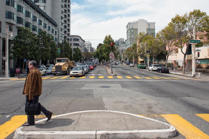 A pedestrian crosses the street at Golden Gate Avenue and Van Ness Avenue