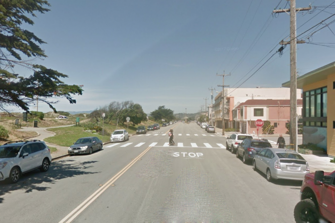 Lower Great Highway approaching Lawton Street, looking north. A pedestrian is crossing in the crosswalk.