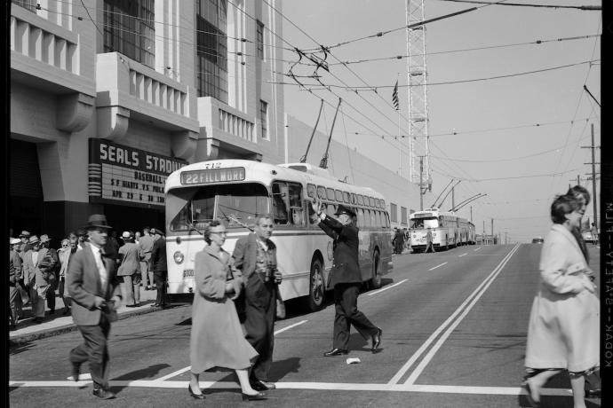 people crossing 16th street outside Seals Stadium with Muni buses in background