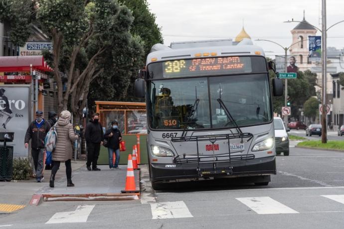 Passengers board a 38R Geary Rapid in the Richmond District with the help of a temporary wooden "bus bulb."