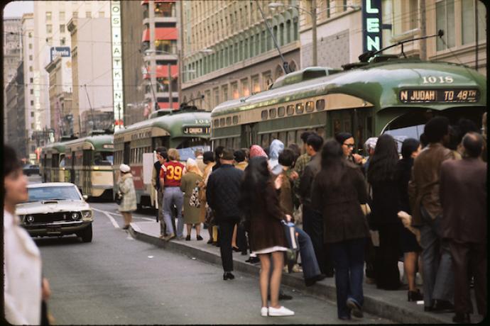 Muni platform overflowing with people waiting for streetcars as people board