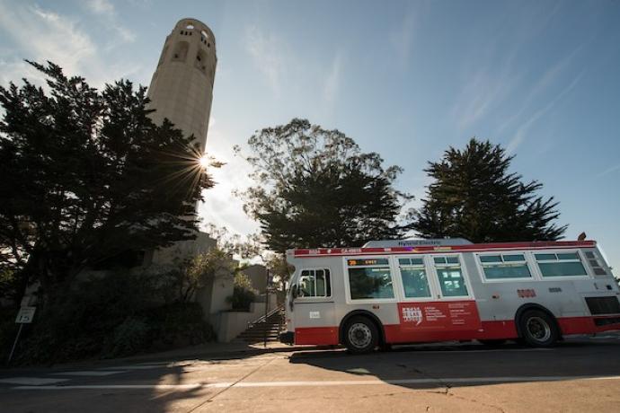 Photo depicting a Muni bus next to Coit Tower.