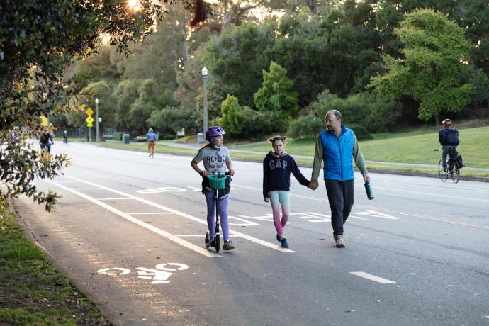 a family walking and scooting on car-free JFK Drive