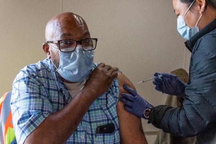 Photo shows a man receiving a vaccination.