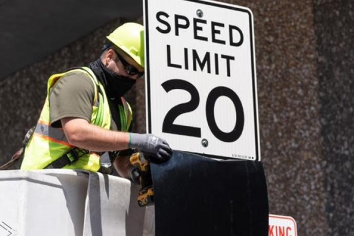 Crew member affixing a new 20 MPH speed limit on Larkin Street. 