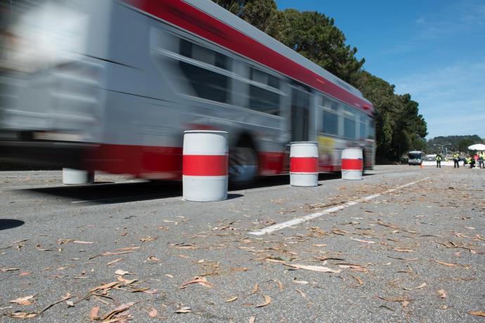 Bus in blurred motion traveling in a parking lot next to barrels 