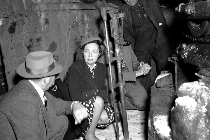 Three people standing next to bus, two people are shaking hands.