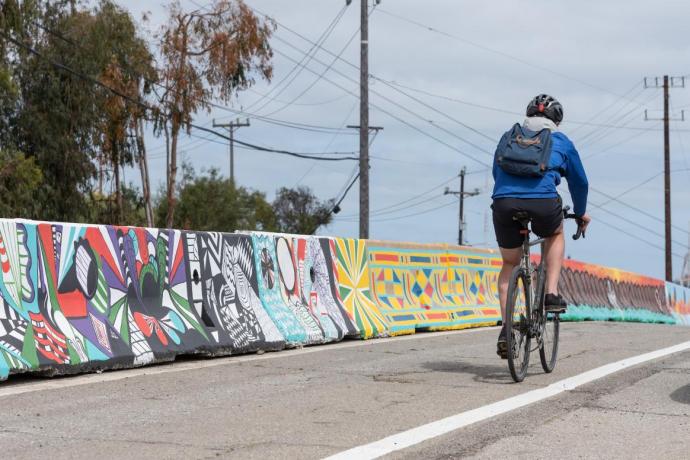 A cyclist is shown traveling in the newly installed bike lane on Hunters Point Boulevard, separated with concrete barriers. 