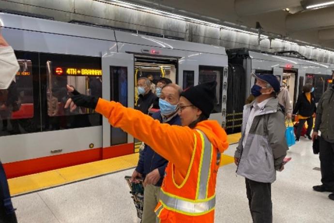 SFMTA Ambassador talking to customers on Metro station platform.