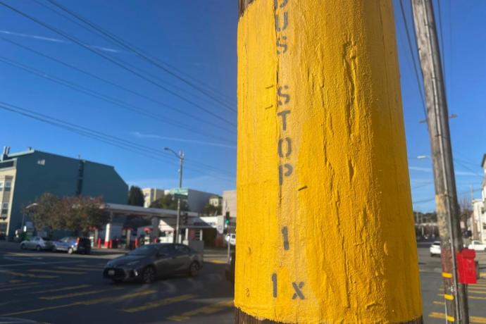 Photo showing a pole on the street painted yellow that says bus stop, 1, 1X