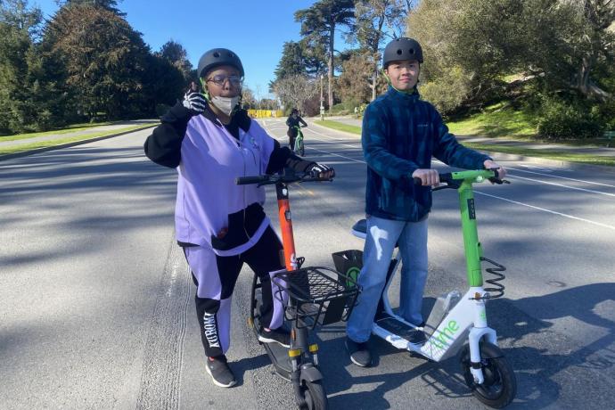 AccessSFUSD students standing with Lime and Spin scooters; one student is giving a thumbs up