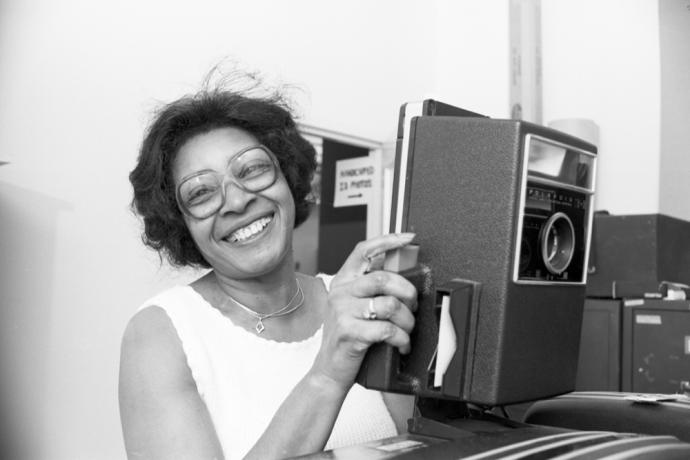 Employee smiling and holding a vintage card camera 
