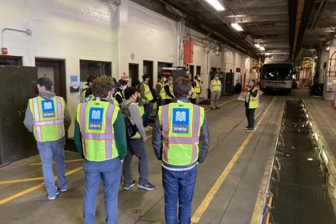 People wear safety vests while inside a transit facility