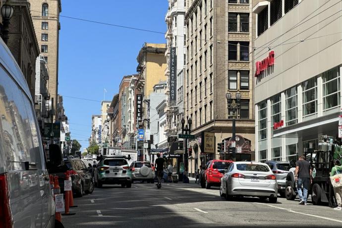 Vehicles and scooter traffic traveling west on Sutter Street, vehicle double parking