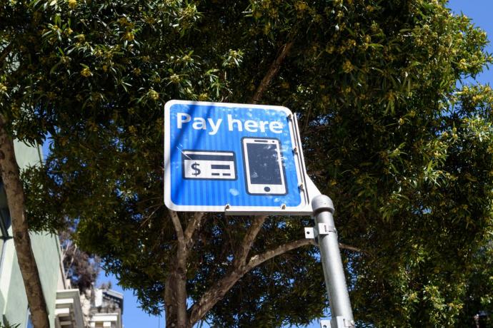 A sign that reads "Pay here" with a picture of a credit card and smartphone.