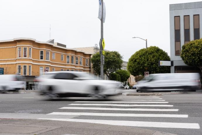 A white car appears blurry as it speeds through an intersection.