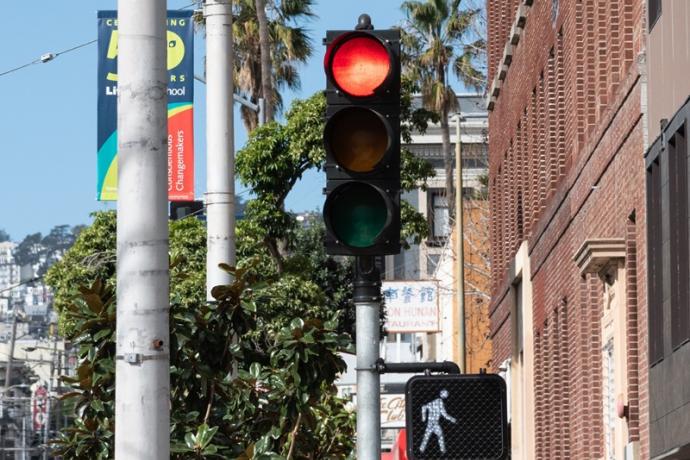 A red vehicular traffic signal adjacent to a white, pedestrian walk signal.