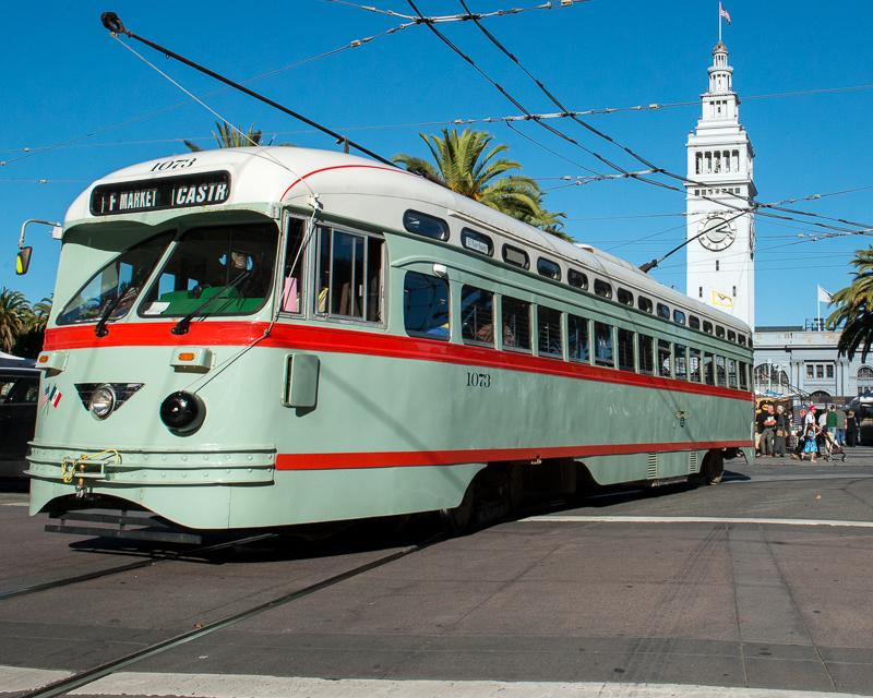 green, white, and red streetcar passing in front of Ferry building on Market Street