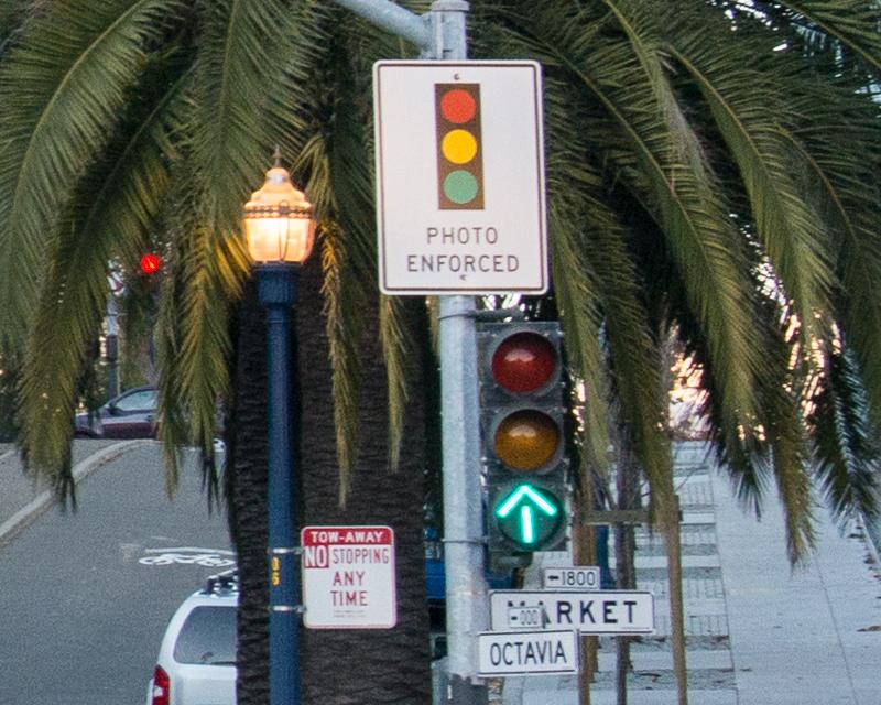 closeup view of traffic signal and sign reading "photo enforced" by redlight cameras