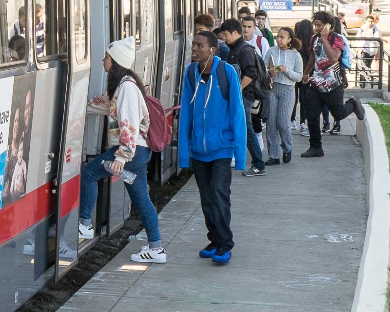 group of teenagers boarding Muni train outside Mission High School in Dolores Park
