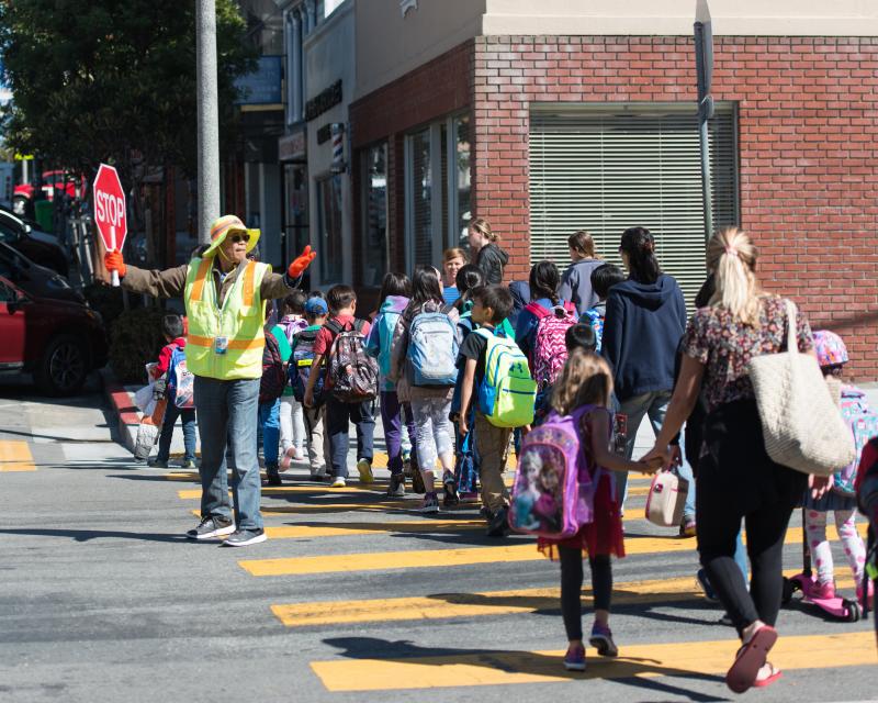 Children crossing street with help of crossing guard