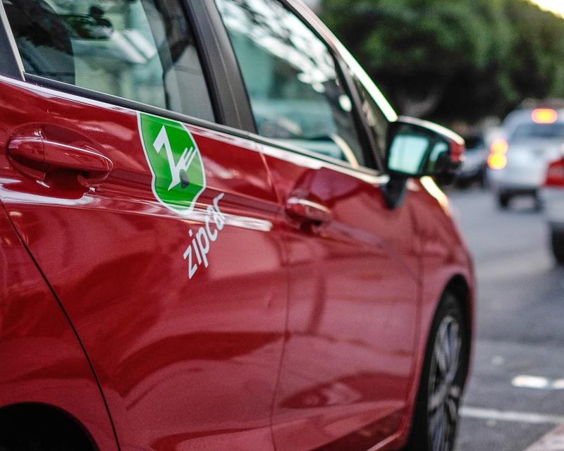 closeup view of red rental car in on-street "car share" parking space