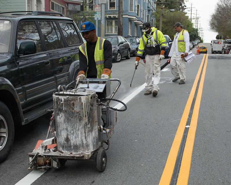 SFMTA crew members apply striping to a street