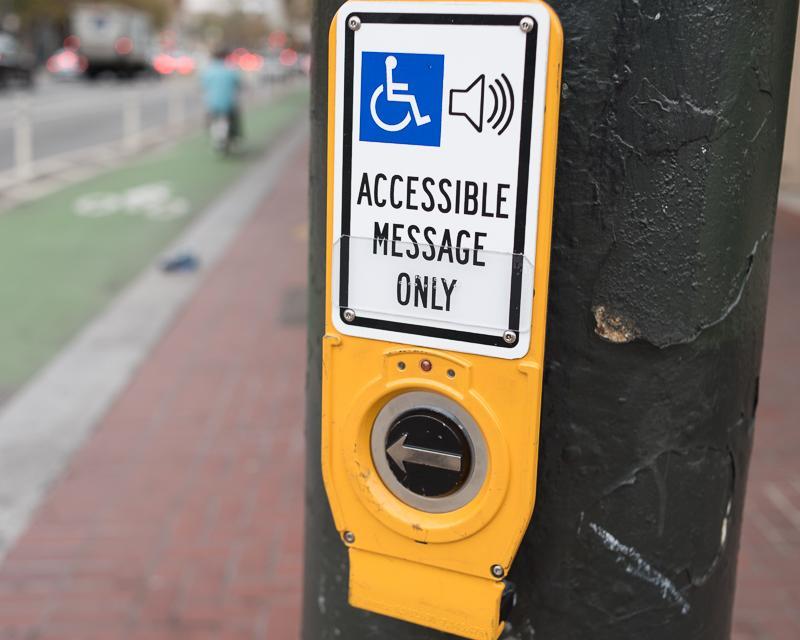 An accessible crossing button: above a press button, a sign reads "accessible message only"