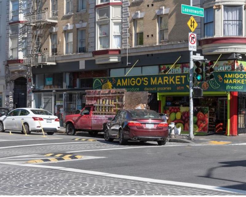 A car makes a left turn through an intersection; there are small speed humps and plastic posts to guide a 90-degree turn