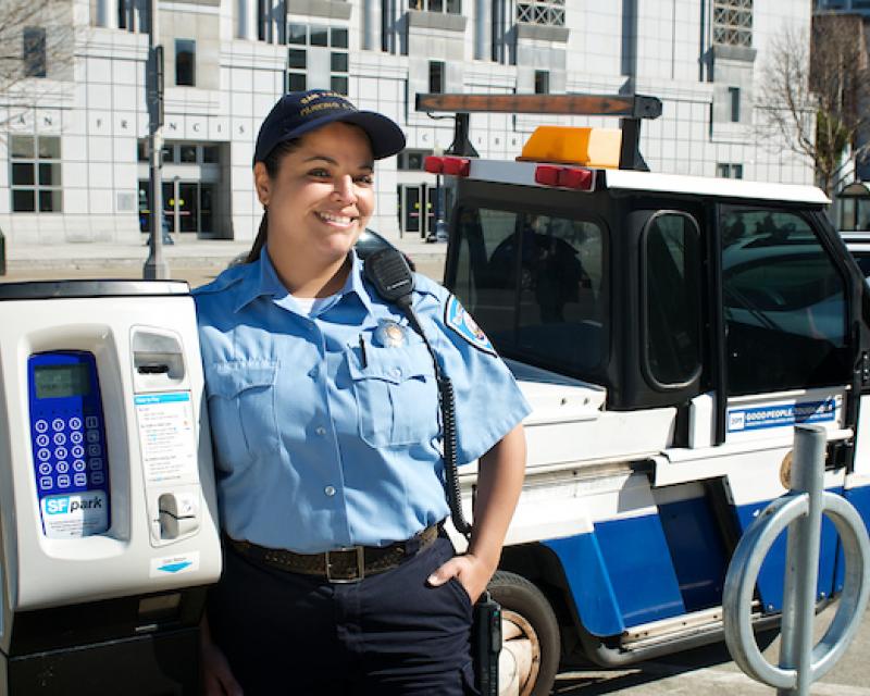 Image of a parking control officer standing by a meter