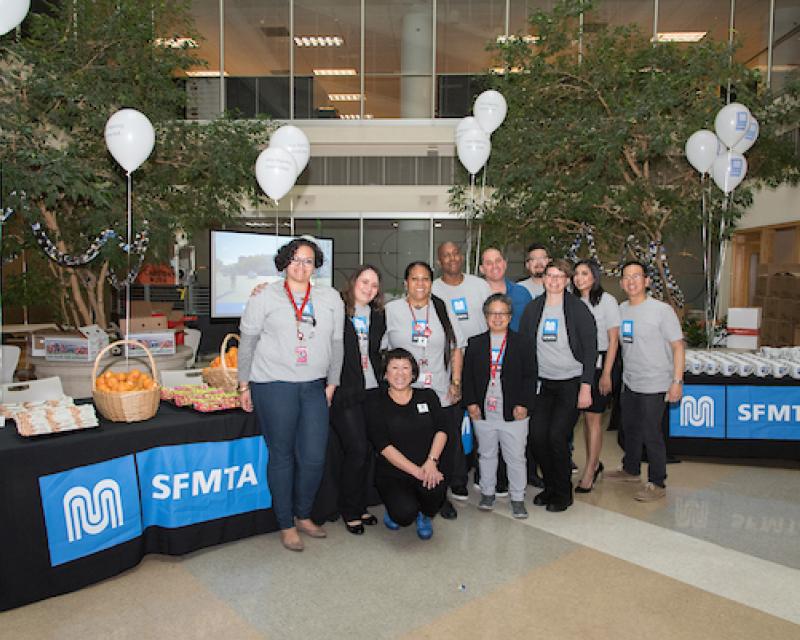 SFMTA Colleagues in front of tables with banners of the logo