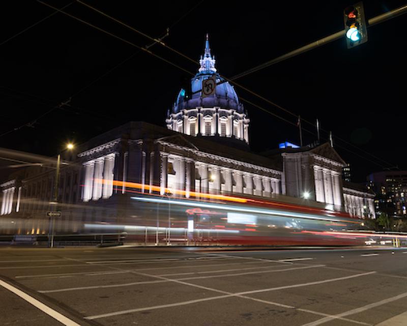 Night shot of City Hall with Van Ness BRT streaming in front