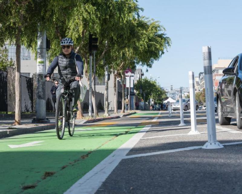 A person riding a bike on the parking-protected bikeway on Folsom Street