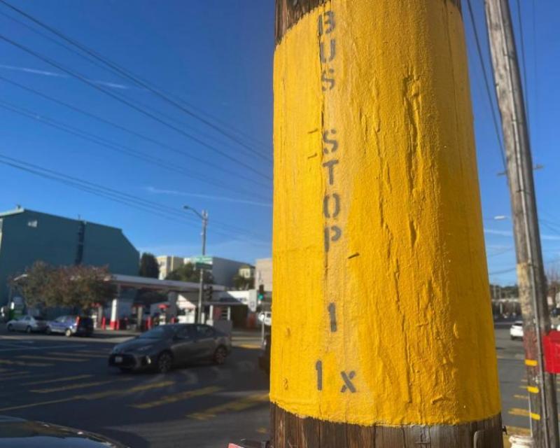 Photo showing a pole on the street painted yellow that says bus stop, 1, 1X