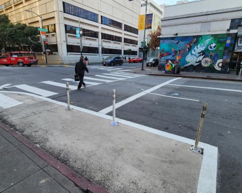Pedestrian crossing in a crosswalk painted safety zone in the foreground