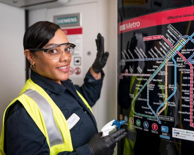 Trina Dixon smiles as she cleans the colorful Muni Metro map on a train.