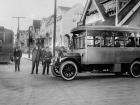 black and white image of people standing outside vintage bus and streetcar