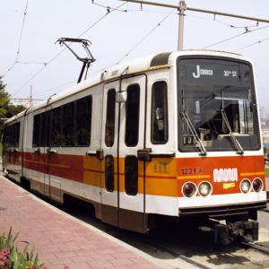 Muni Boeing LRV at outbound stop at top of hill in dolores park in the 1980s with a view of the city skyline behind it