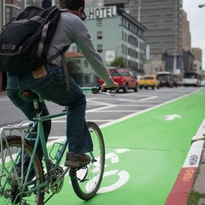 A man bikes on a parking-protected bike lane on 7th Street. 