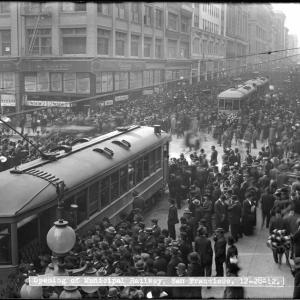crowd of people with streetcars in street in 1912