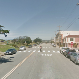 Lower Great Highway approaching Lawton Street, looking north. A pedestrian is crossing in the crosswalk.