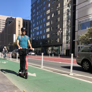 A person wearing a helmet rides a scooter in a bike lane