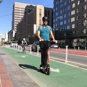 A person wearing a helmet rides a scooter in a bike lane