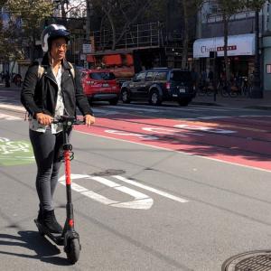 Lady on scooter riding with helmet.