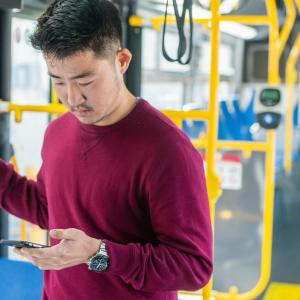 Man on bus checking his phone