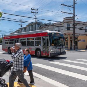 27 Bryant and two people crossing with a stroller on Bryant Street at 20th St in the Mission  