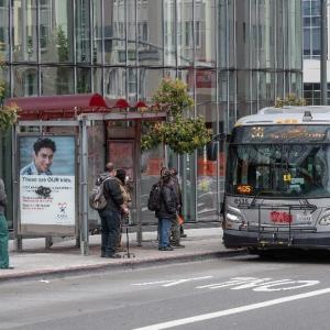 Photo of passengers at a bus shelter as a bus is arriving