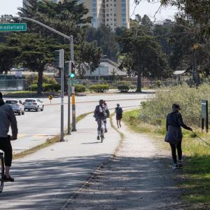 Photo of pedestrians, people on bicycles, and cars on Lake Merced Boulevard