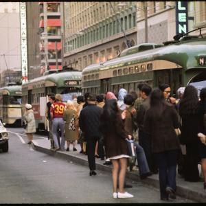 Muni platform overflowing with people waiting for streetcars as people board