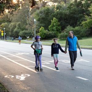 a family walking and scooting on car-free JFK Drive